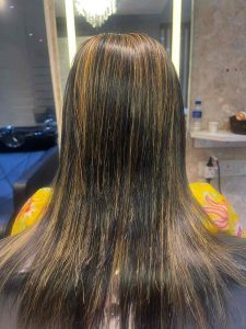 A woman with long, dark hair getting styled at a salon.