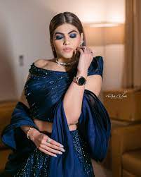 A beautiful woman in a blue sari, standing gracefully with a serene expression.