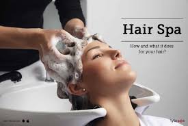 A woman receiving a hair spa treatment at a salon, with various hair products displayed around her.